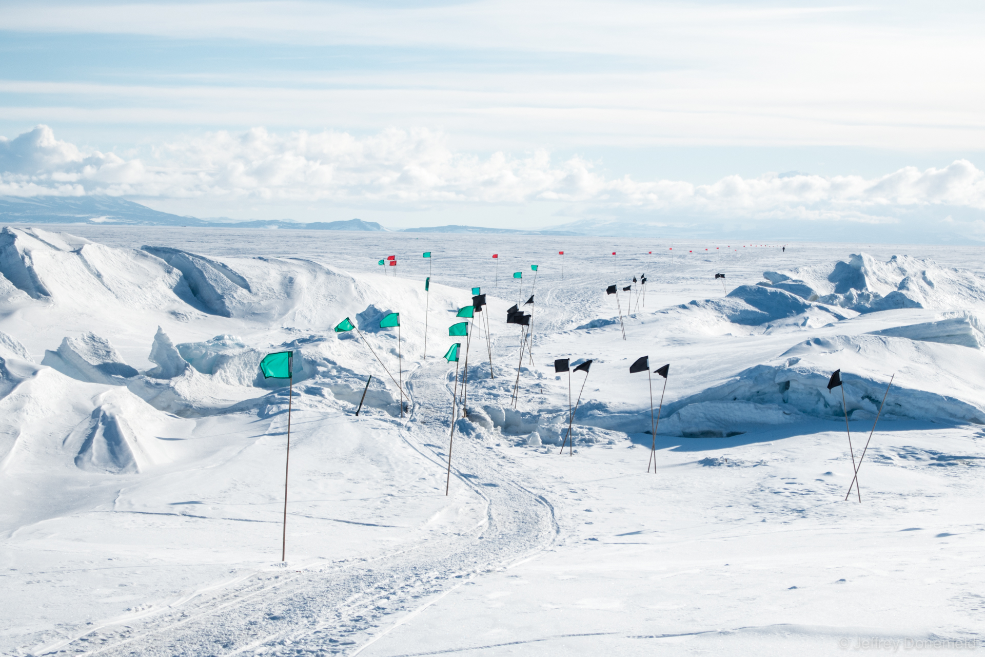 Entering the ice ridges on the frozen sea ice of McMurdo Sound. Colored flags mark the way through the ridges, on areas known to be solid. Amongs the ridges are huge cracks in the ice, leading to think ice and the Ross Sea.